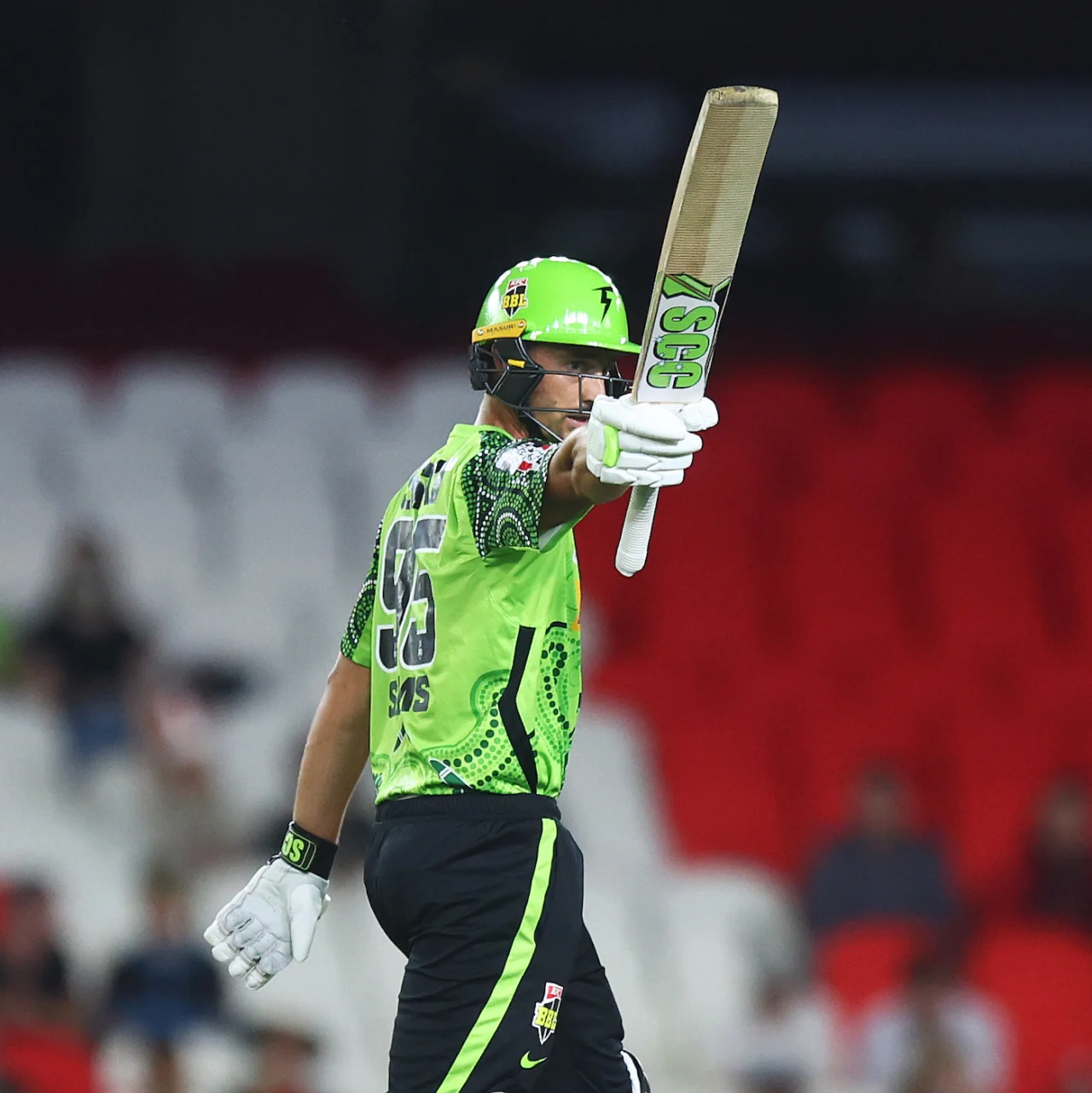 Daniel Sams raises his SCC Players cricket bat after reaching 50 runs for the Sydney Thunder against the Adelaide Strikers at Manuka Oval, Canberra